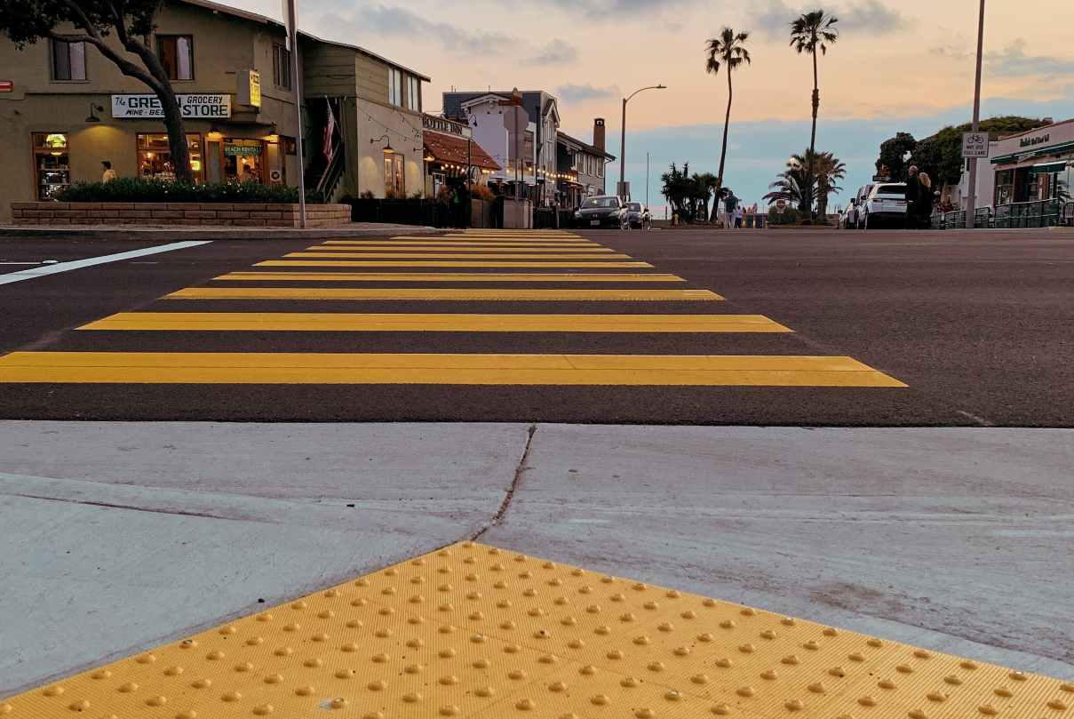 image of truncated domes of curb ramp and yellow ladder crosswalk on recently paved road